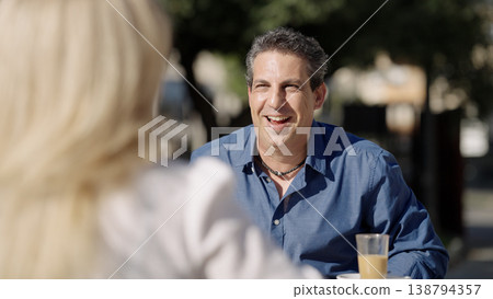 Man laughing and enjoying a conversation at outdoor cafe 138794357