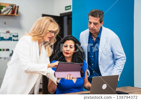 Business colleagues collaborating on digital tablet in office Business colleagues collaborating on digital tablet in office 138794372