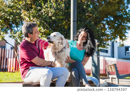 Happy couple petting golden retriever dog in park Happy couple petting golden retriever dog in park 138794397