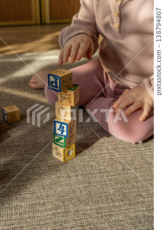 A little girl playing with colorful wooden blocks on the floor. A little girl playing with colorful wooden blocks on the floor. 138794807