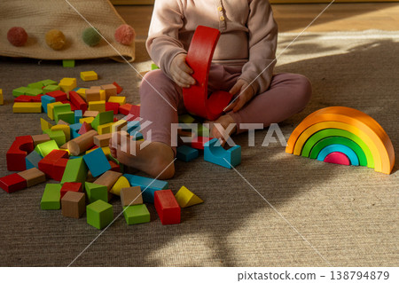 A little girl playing with colorful wooden blocks on the floor. A little girl playing with colorful wooden blocks on the floor. 138794879