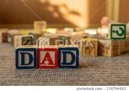 Baby stacking wooden blocks in a word dad. Concept of Fathers day. Baby stacking wooden blocks in a word dad. Concept of Fathers day. 138794883