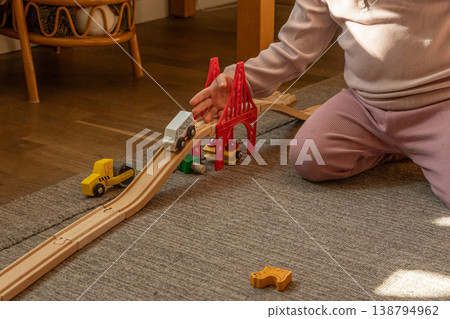 A little girl playing with wooden toy trains on the floor. A little girl playing with wooden toy trains on the floor. 138794962