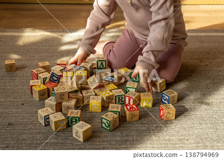 A little girl playing with colorful wooden blocks on the floor. A little girl playing with colorful wooden blocks on the floor. 138794969