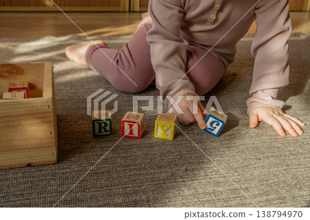 A little girl playing with colorful wooden blocks on the floor. A little girl playing with colorful wooden blocks on the floor. 138794970