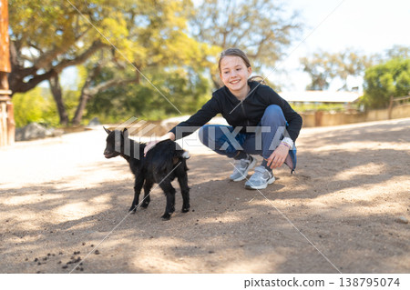 Young girl petting sweet black baby goat 138795074