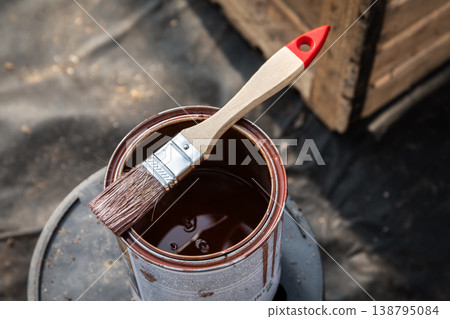Paintbrush Resting on Open Can of Brown Paint During Renovation Work 138795084