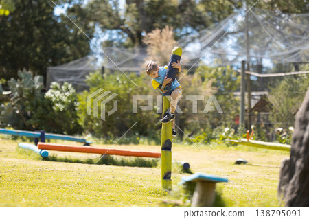 Young boy climbing tall wooden playground pole 138795091