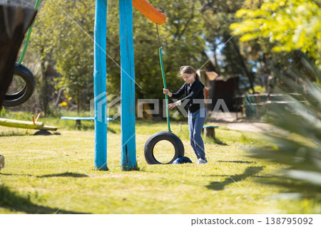 Girl playing with tire swing on playground 138795092