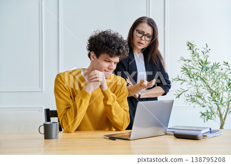 Confident female mentor teacher advising teaching male university student Confident female mentor teacher advising teaching male university student 138795208