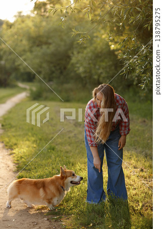 An Outdoor Scene Featuring Woman And Her Corgi Appreciating Nature During Golden Hour An Outdoor Scene Featuring Woman And Her Corgi Appreciating Nature During Golden Hour 138795275