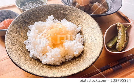 A traditional Japanese breakfast: a Japanese set meal consisting of rice with a raw egg on top and a small side dish. A traditional Japanese breakfast: a Japanese set meal consisting of rice with a raw egg on top and a small side dish. 138795554