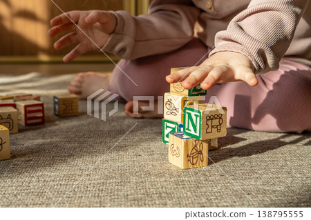 A little girl playing with colorful wooden blocks on the floor. A little girl playing with colorful wooden blocks on the floor. 138795555