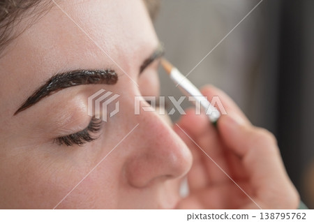 Caucasian woman getting eyebrow tinting procedure. Caucasian woman getting eyebrow tinting procedure. 138795762
