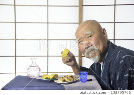 A bearded old man drinking sake in a Japanese-style room. A bearded old man drinking sake in a Japanese-style room. 138795766