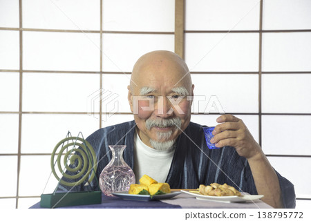 A bearded old man drinking sake in a Japanese-style room. A bearded old man drinking sake in a Japanese-style room. 138795772