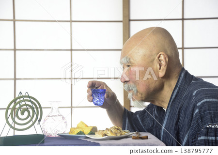 一位留著鬍子的老人在日式房間喝清酒。 一位留著鬍子的老人在日式房間喝清酒。 138795777