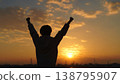 A person spreading their arms towards the setting sun 138795907