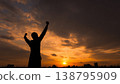 A person spreading their arms towards the setting sun 138795909