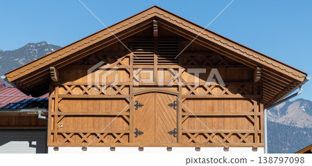 Symmetrical wooden chalet facade detail with alpine mountain background Symmetrical wooden chalet facade detail with alpine mountain background 138797098