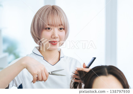 A female staff member with light-colored hair cutting hair. A female staff member with light-colored hair cutting hair. 138797930