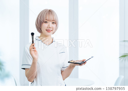 一名淺色頭髮的女工作人員手持美髮和化妝工具。 138797935