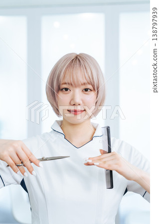 淺色頭髮的女員工手持理髮工具。 淺色頭髮的女員工手持理髮工具。 138797939