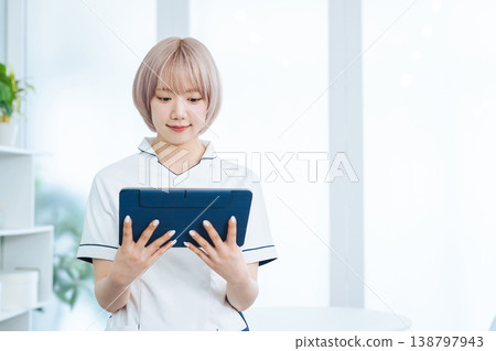 A female staff member with light-colored hair is looking at a tablet PC. A female staff member with light-colored hair is looking at a tablet PC. 138797943