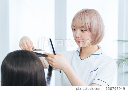 一名淺色頭髮的女員工正在剪頭髮。 138797949