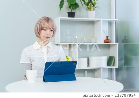A woman with light-colored hair looking at a tablet PC. 138797954
