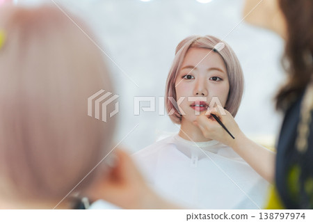 A woman with light-colored hair getting her hair and makeup done. 138797974