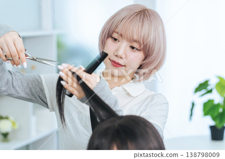 A female staff member with light-colored hair cutting hair. A female staff member with light-colored hair cutting hair. 138798009