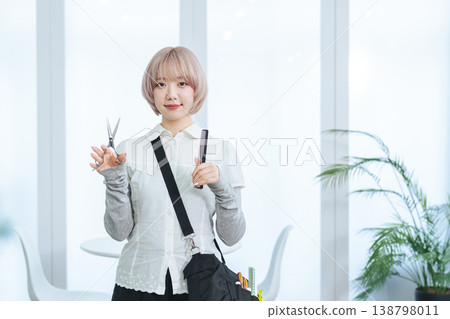 A female staff member with light-colored hair holding hair cutting tools. 138798011