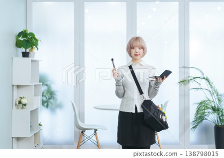 一名淺色頭髮的女工作人員手持美髮和化妝工具。 一名淺色頭髮的女工作人員手持美髮和化妝工具。 138798015