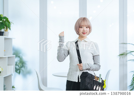 A female staff member with light-colored hair holding hair and makeup tools. 138798016