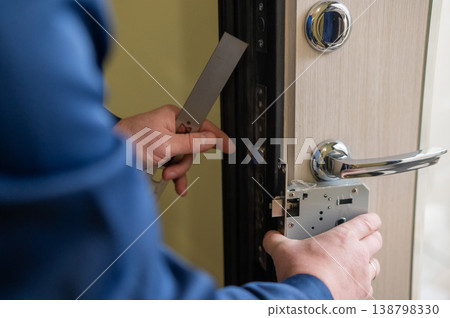 The technician installs a smart electronic lock on the front door. 138798330