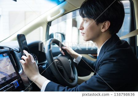 Businessmen operating their smartphones while driving. Businessmen operating their smartphones while driving. 138798636