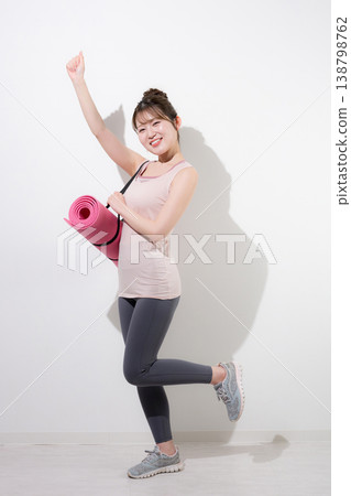 A woman with a yoga mat against a white background, healthy and beautiful, training in the gym and lifestyle. 138798762