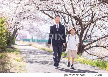 A high school student and an elementary school boy walking hand in hand under the cherry blossoms. A high school student and an elementary school boy walking hand in hand under the cherry blossoms. 138798810