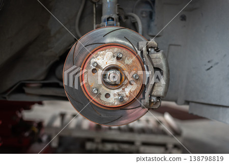Closeup of car brake disc and caliper showing worn metal surface and mechanical details automotive maintenance repair concept with industrial background Closeup of car brake disc and caliper showing worn metal surface and mechanical details automotive maintenance repair concept with industrial background 138798819