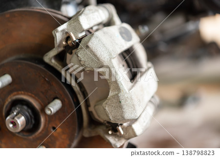 Closeup of car brake caliper and disc showing metal surface and mechanical detail automotive repair maintenance concept in workshop environment Closeup of car brake caliper and disc showing metal surface and mechanical detail automotive repair maintenance concept in workshop environment 138798823