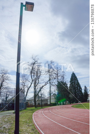 Under a cloudy sky, a well-maintained, open athletics track surrounded by green grass is open to everyone. Under a cloudy sky, a well-maintained, open athletics track surrounded by green grass is open to everyone. 138798878
