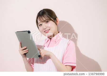 The pink background shows women working as caregivers or childcare workers in home care jobs, pointing to and holding tablets as they become more digitized. 138798990
