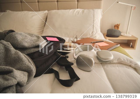 Backpack with headphones and study materials on bed Backpack with headphones and study materials on bed 138799319