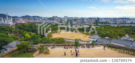Himeji, Japan - Sep 24 2024, panoramic aerial view from window of White Heron Castle to park in front of castle and city of Himeji, with people on courtyard, at daytime with cloudy sky, Himeji, Japan 138799374
