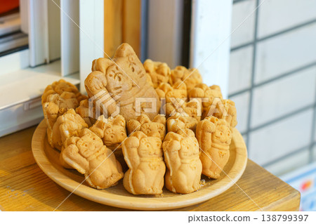 Tokyo, Japan - Sep 30 2024, A close-up view of a bowl filled with Taiyaki pies in the form of a Maneki Neko, in the window of a cafe, Tokyo, Japan 138799397