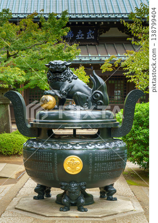 Tokyo, Japan - Sep 30 2024, vertical view of the bronze incense burner decorated with a lion statue, surrounded by trees, on road to Gotokuji Temple, without people, at daytime, Tokyo, Japan Tokyo, Japan - Sep 30 2024, vertical view of the bronze incense burner decorated with a lion statue, surrounded by trees, on road to Gotokuji Temple, without people, at daytime, Tokyo, Japan 138799404