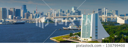 Tokyo, Japan - Oct 2 2024, panoramic aerial view of Tokyo Bay cityscape in background and the Rainbow Bridge, in the foreground is a part of Odaiba Island with a triangular building, Tokyo, Japan 138799408