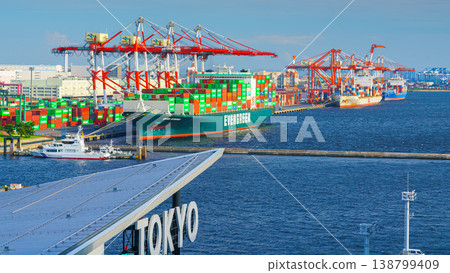 Tokyo, Japan - Oct 2 2024, panoramic view of docks with cranes and a moored giant cargo ship loaded with containers, in foreground is signage with word Tokyo on roof of Tokyo cruise port, Tokyo, Japan Tokyo, Japan - Oct 2 2024, panoramic view of docks with cranes and a moored giant cargo ship loaded with containers, in foreground is signage with word Tokyo on roof of Tokyo cruise port, Tokyo, Japan 138799409