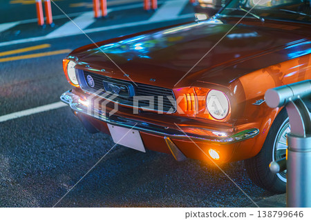 Tokyo, Japan - Oct 15 2024, Close-up view of the front bumper hood and burning headlights of a retro Ford Mustang, on one of the roads of Tokyo, at nighttime, Tokyo, Japan Tokyo, Japan - Oct 15 2024, Close-up view of the front bumper hood and burning headlights of a retro Ford Mustang, on one of the roads of Tokyo, at nighttime, Tokyo, Japan 138799646